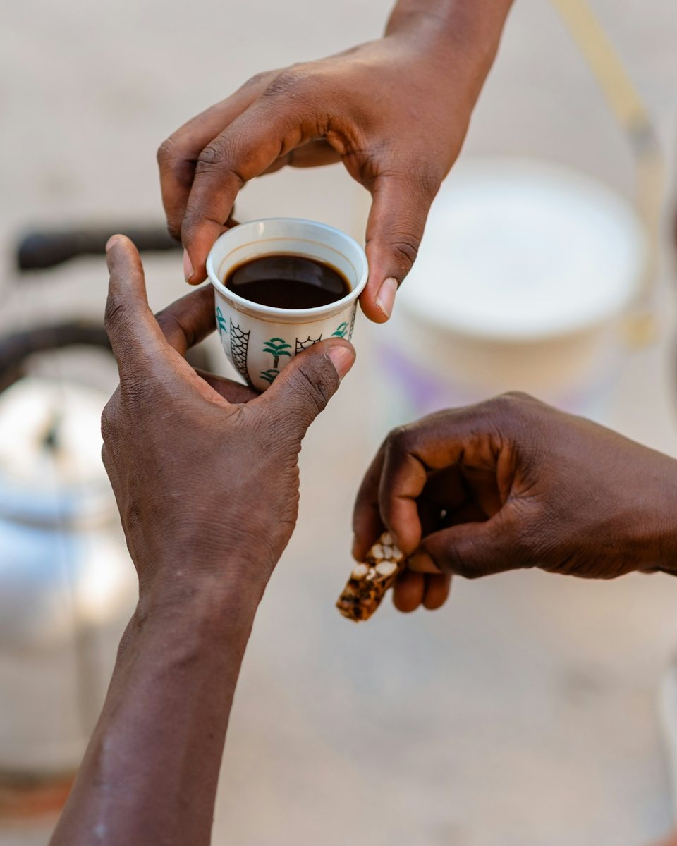 Hands offering a small cup of coffee during a ceremony
