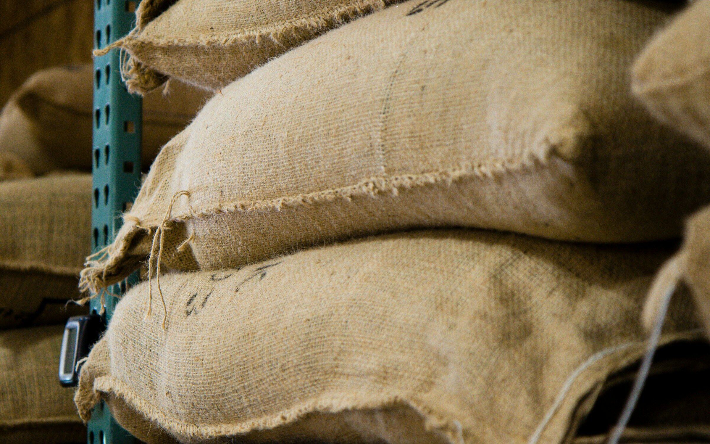 Burlap sacks of coffee stacked on pallets in a warehouse